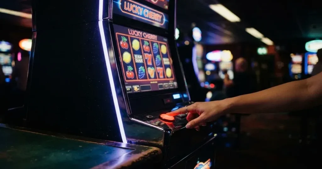 Ett finger trycker på spelautomatens klarröda knapp i dunklet, neonljus lyser runt omkring — 100 free spins casino i sverige