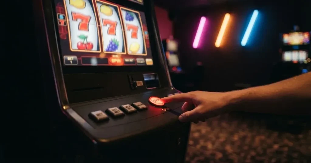 Ett finger trycker på spelautomatens klarröda knapp i dunklet, neonljus lyser runt omkring — 150 free spins casino i sverige